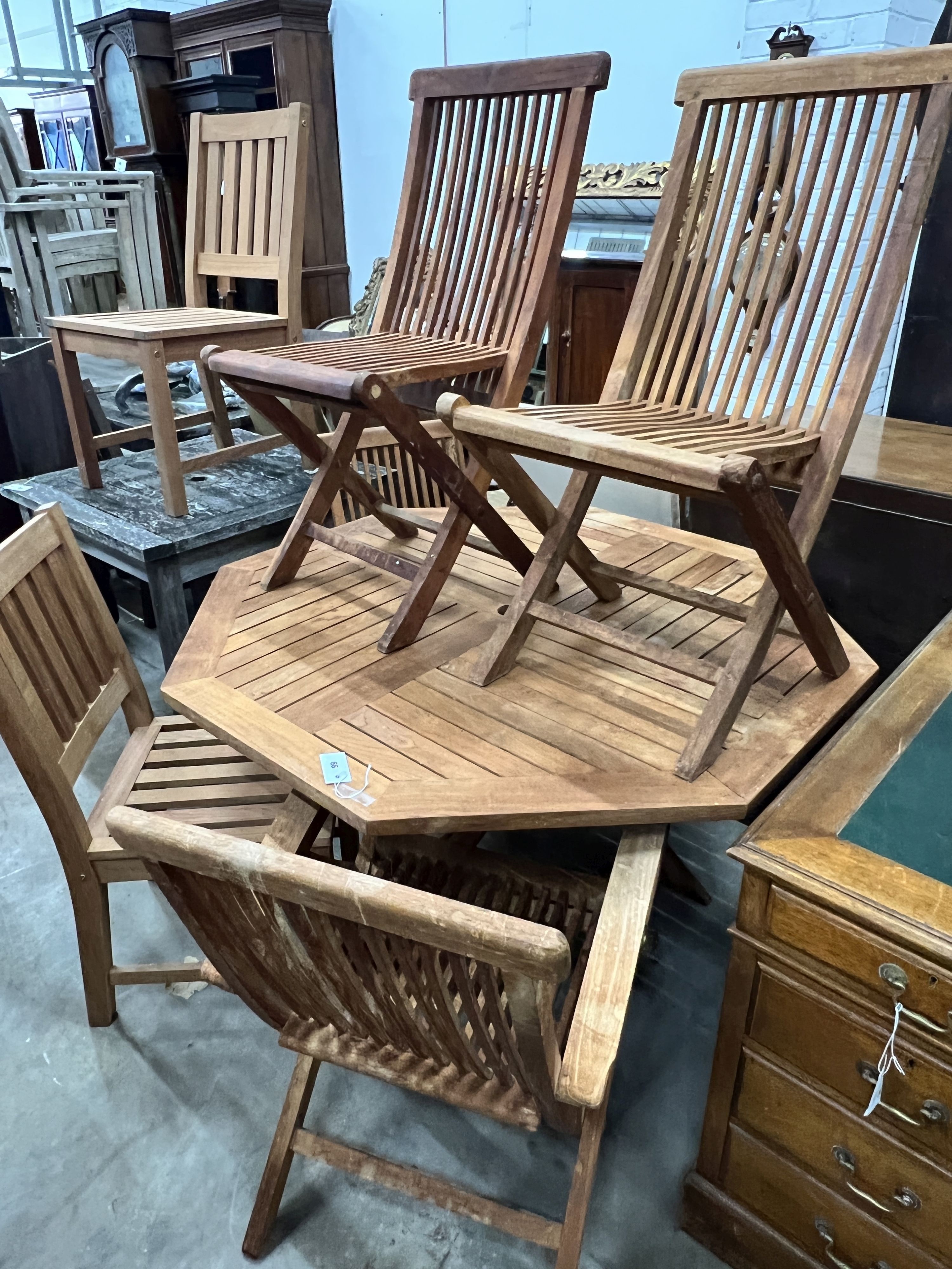 An octagonal teak folding garden table, length 120cm, height 74cm and four folding teak garden chairs, two with arms